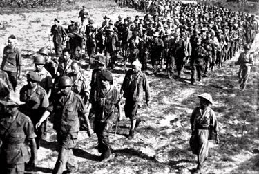 French soldiers march to a prisoner of war camp after they surrendered to the Viet Minh forces after the Battle of Dien Bien Phu
