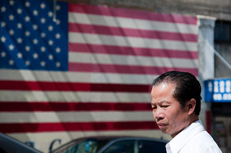 Photo of man of Asian descent in front of American flag
