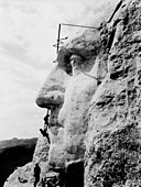 Profile of stone face on mountainside, with 3 workers.